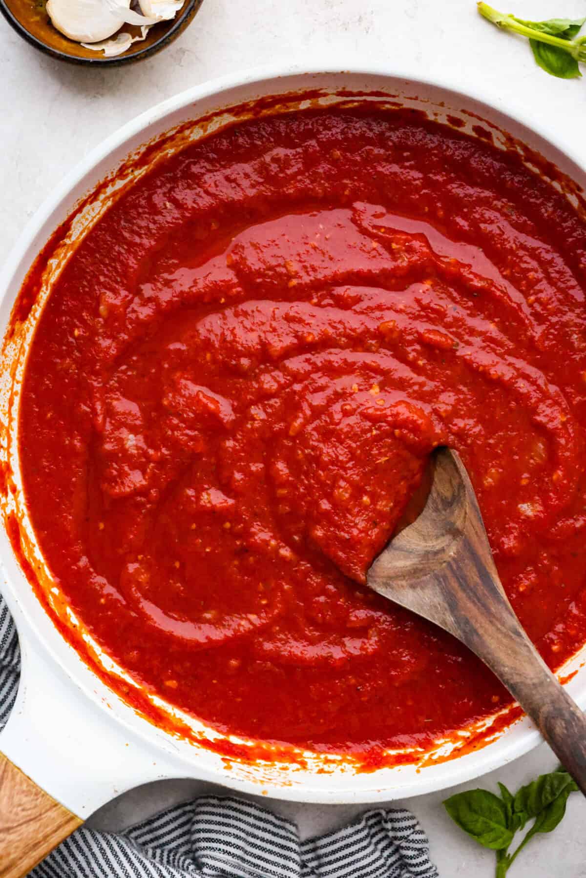 After re-testing this Homemade Marinara Sauce, I can confidently say it’s the BEST! You can make it in 15 minutes, but letting it simmer makes the flavors even better! Top down shot of homemade marinara sauce in a saucepan with wooden serving spoon.